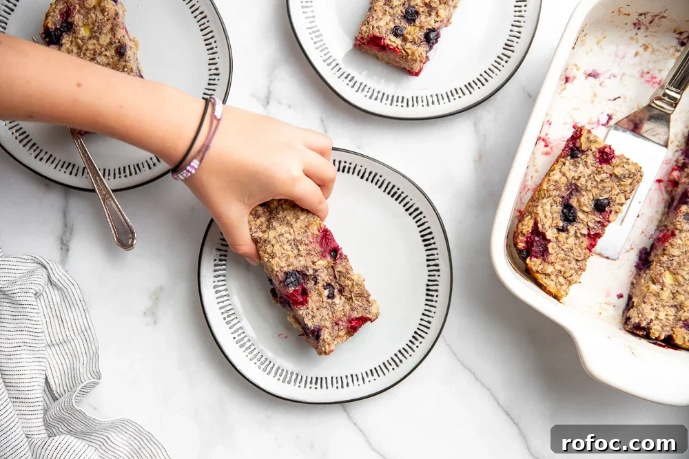Vegan Gluten-Free Baked Oatmeal Bars Made with Natural Sweeteners 4 Hand grabbing an oatmeal bar off of a plate.