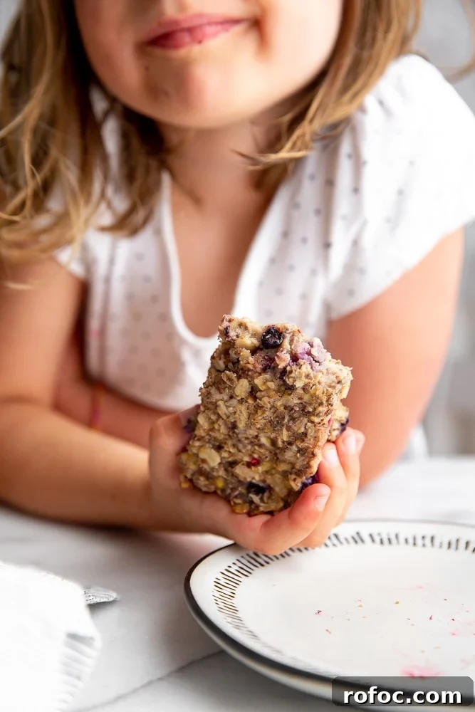 Vegan Gluten-Free Baked Oatmeal Bars Made with Natural Sweeteners 7 Child holding baked oatmeal bar in her hand.