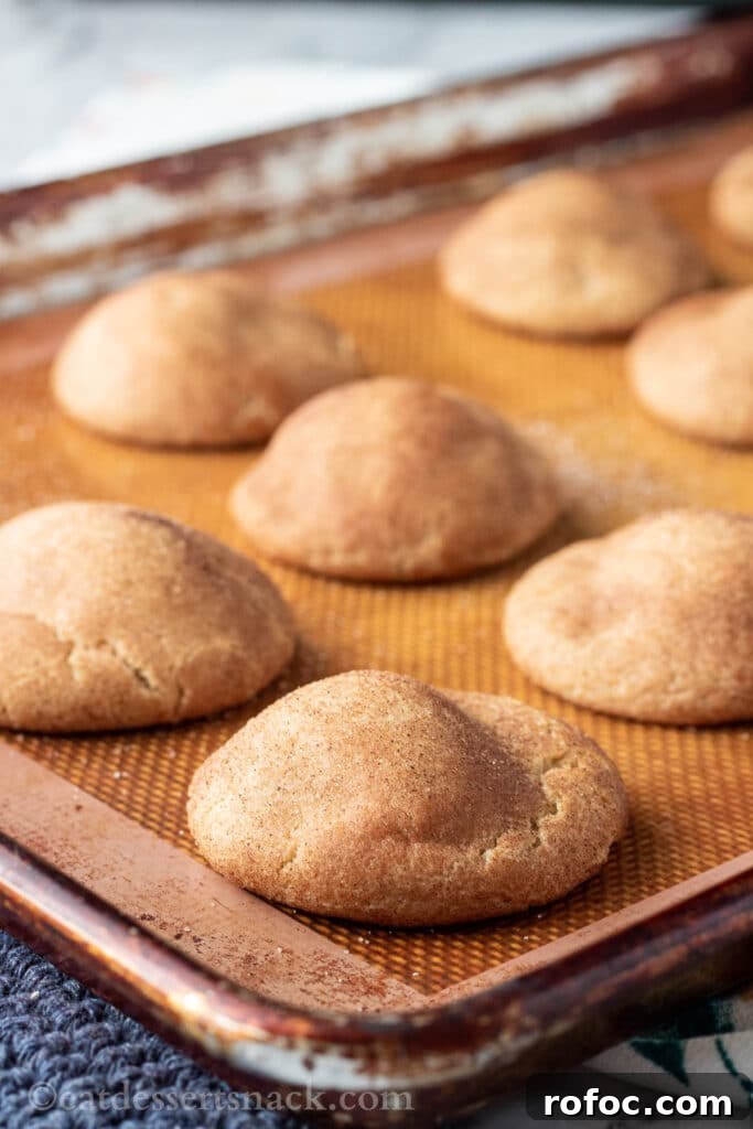 Caramel-Filled Snickerdoodles: Gooey Cinnamon Cookie Recipe 4 Baked caramel stuffed snickerdoodles on metal pan.