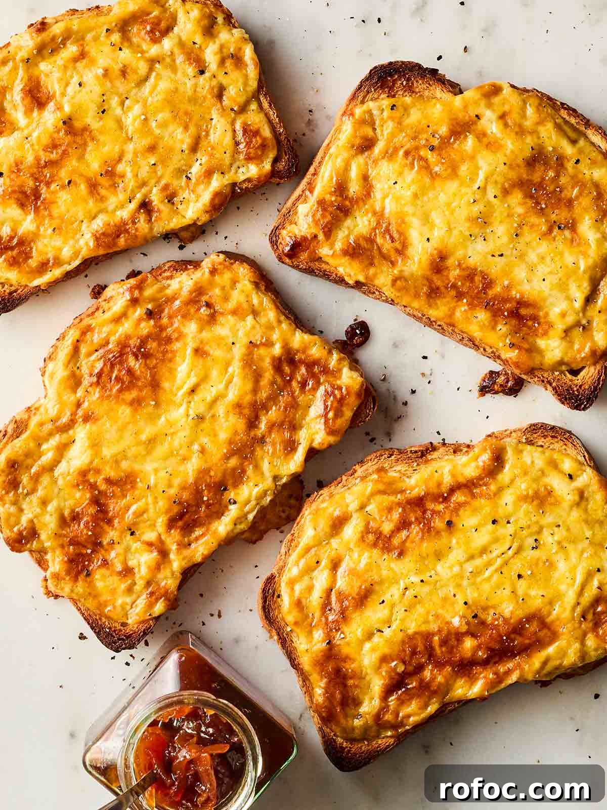 Classic Welsh Rarebit Recipe: Savory Cheese Toast with Ale 2 Four slices of Welsh rarebit with chutney on the side.