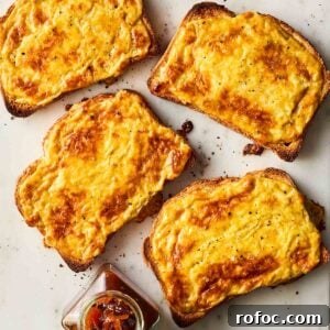 Four slices of Welsh rarebit - cheese on toast with beer - on a white surface.