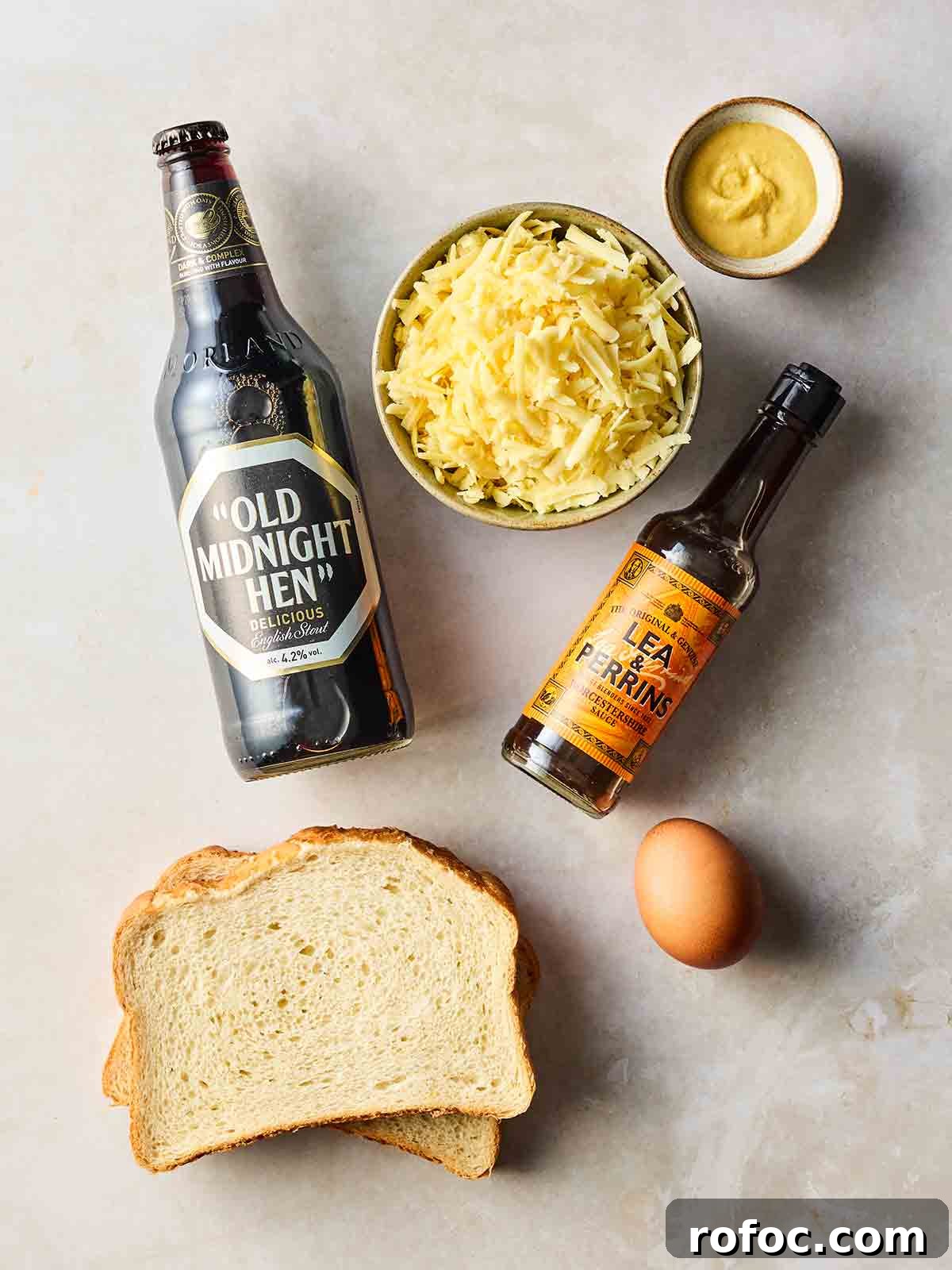 Classic Welsh Rarebit Recipe: Savory Cheese Toast with Ale 4 The ingredients for making Welsh rarebit laid out on a white surface.