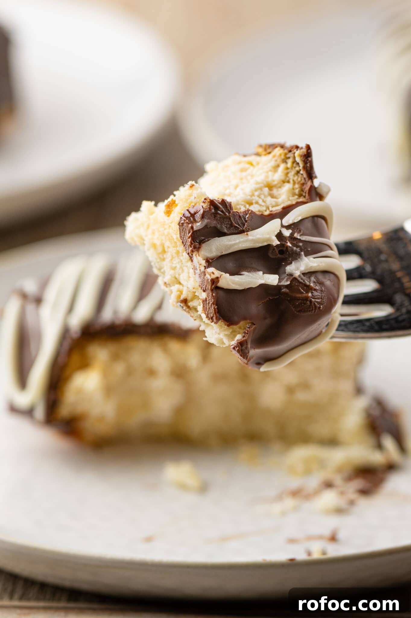 A fork with a piece of keto cheesecake bite coated in chocolate. 