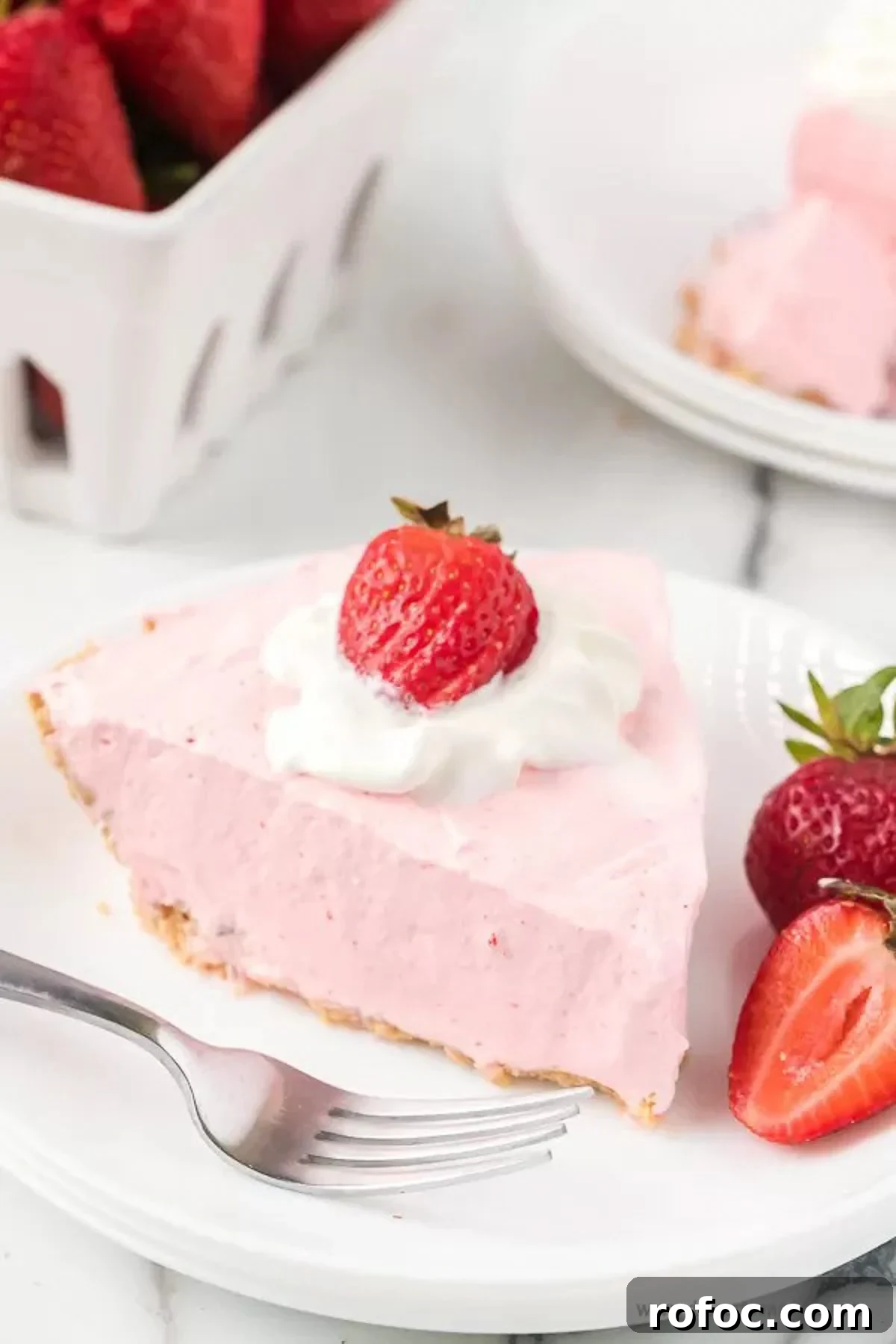 Strawberry jello pie recipe is an easy and classic dessert you can make in minutes. Retro Strawberry jello pie recipe is so light and fluffy and you only need 5 ingredients! Strawberry jello pie cool whip recipe with no bake graham cracker crust makes Strawberry jello pie easy. #dessertonadime #strawberryjellopierecipe Strawberry Jello pie with a side of slice strawberries on a white plate