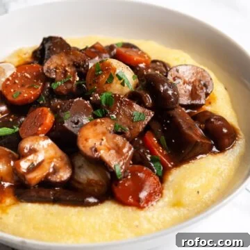 A close up of a bowl of mushroom bourguignon served over polenta.