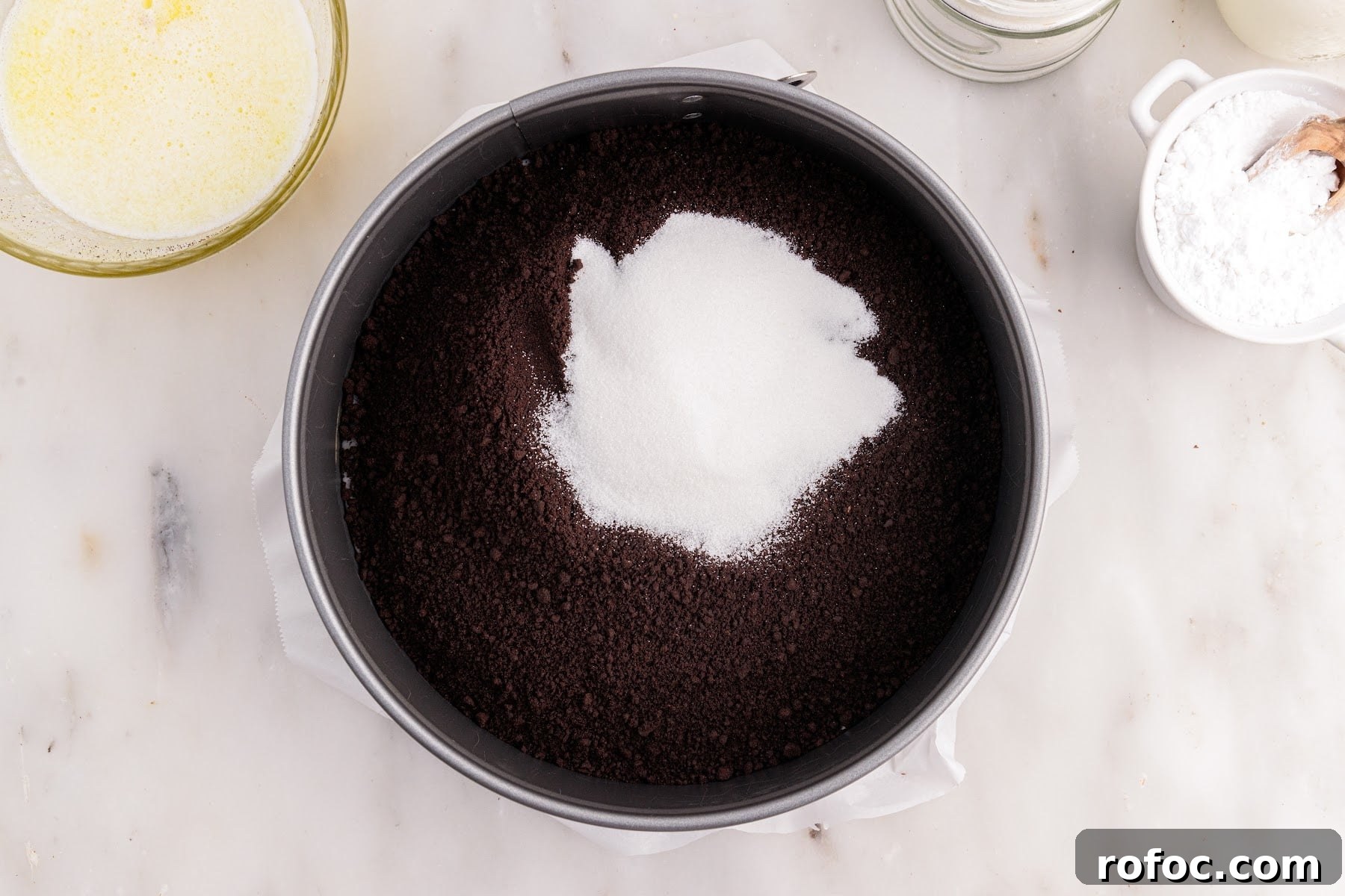 Chocolate graham cracker crumbs and sugar in a spring form pan.