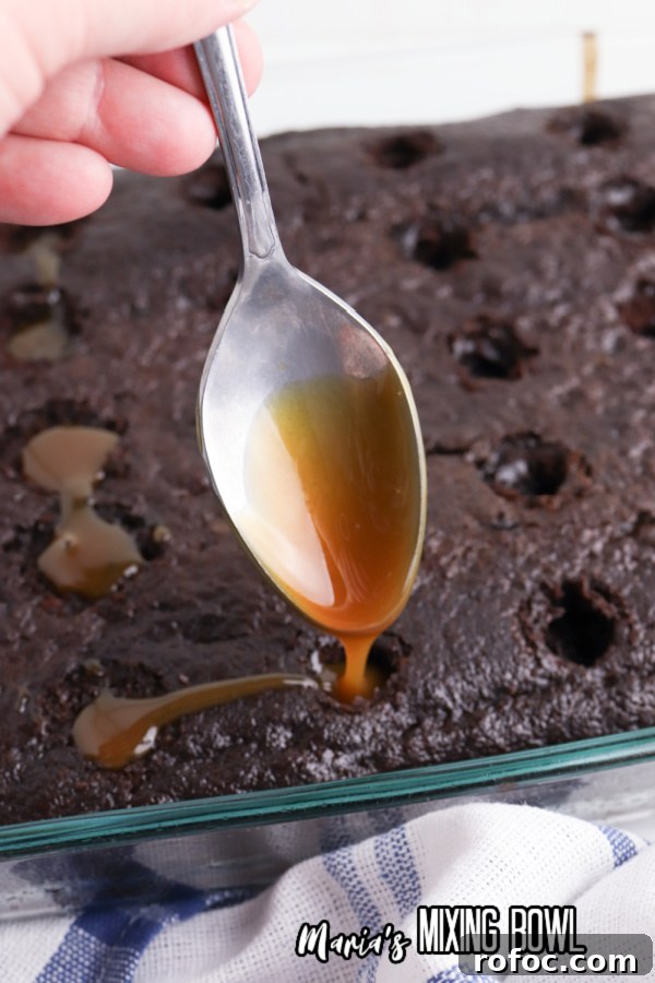 Decadent Snickers Poke Cake: Gooey Chocolate-Caramel Dessert 4 Spoon filling holes in cake with caramel