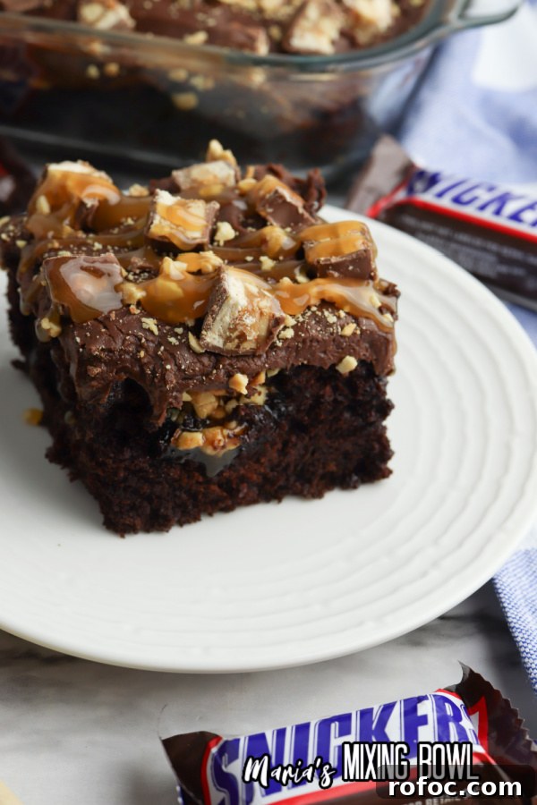 Decadent Snickers Poke Cake: Gooey Chocolate-Caramel Dessert 8 Closeup shot of slice of Snickers poke cake on plate