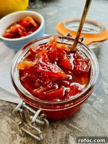 Close up of deep orange-red quince jam in a preserve jar