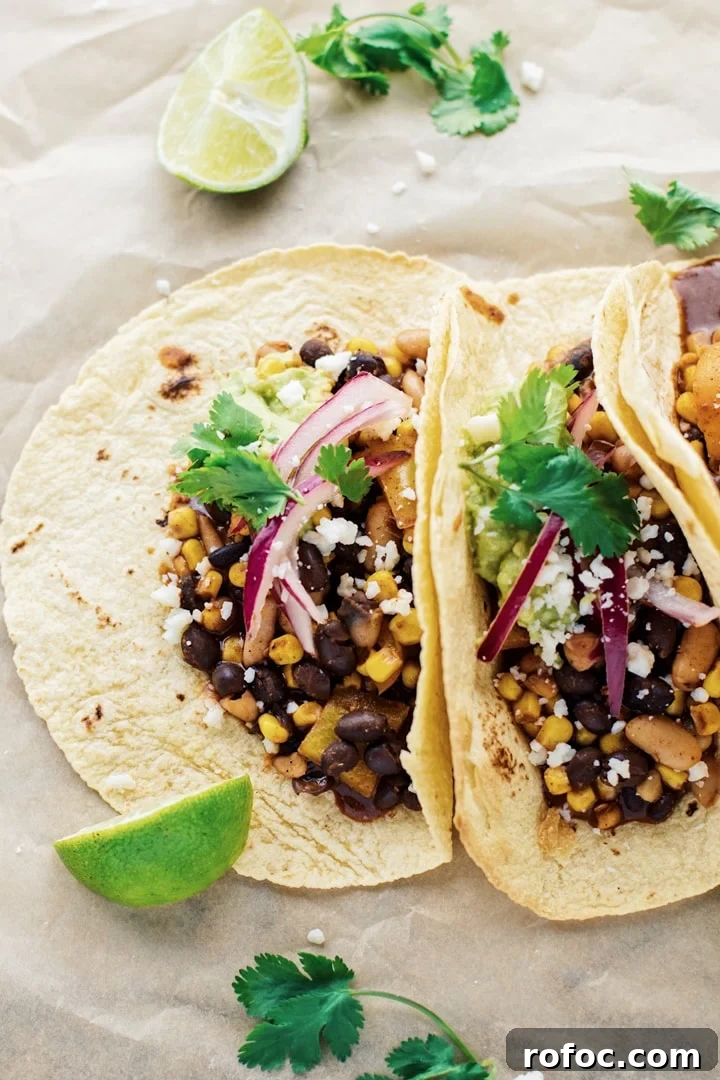 30-Minute Vegetarian Taco Recipe for Busy Weeknights 2 Vegetarian tacos on brown parchment paper with cilantro and lime laid out around it.