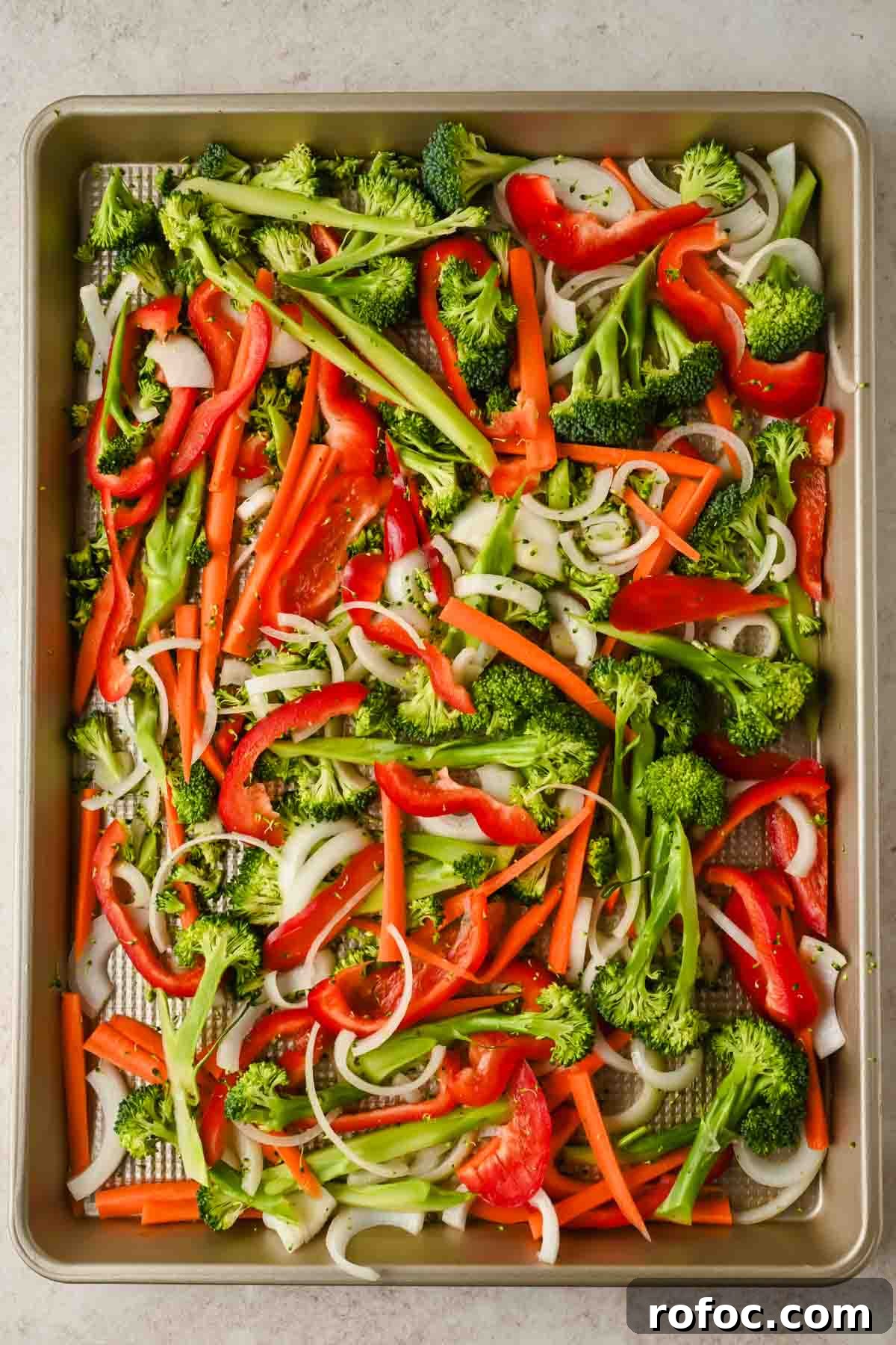Crispy Sheet-Pan Chow Mein: Quick One-Pan Asian Noodle Bake 5 chopped raw broccoli, carrots, white onion and red bell pepper on sheet pan.