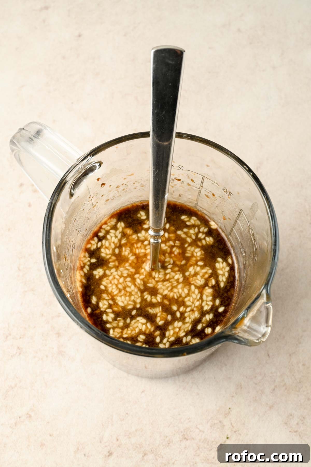 Crispy Sheet-Pan Chow Mein: Quick One-Pan Asian Noodle Bake 6 chow mein sauce with sesame seeds mixed in in glass beaker.