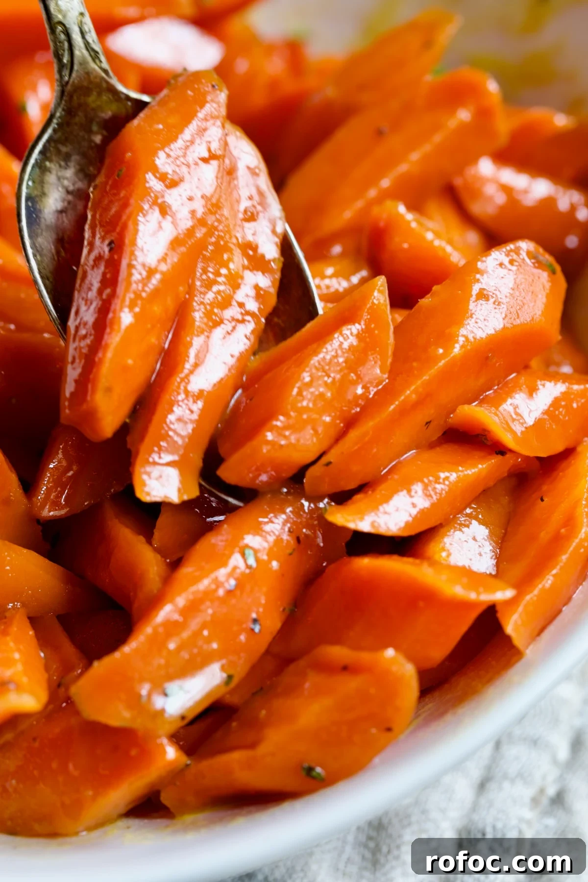 Bourbon-Glazed Carrots with Honey and Fresh Thyme 3 Bourbon-Glazed Carrots being spooned into white bowl.