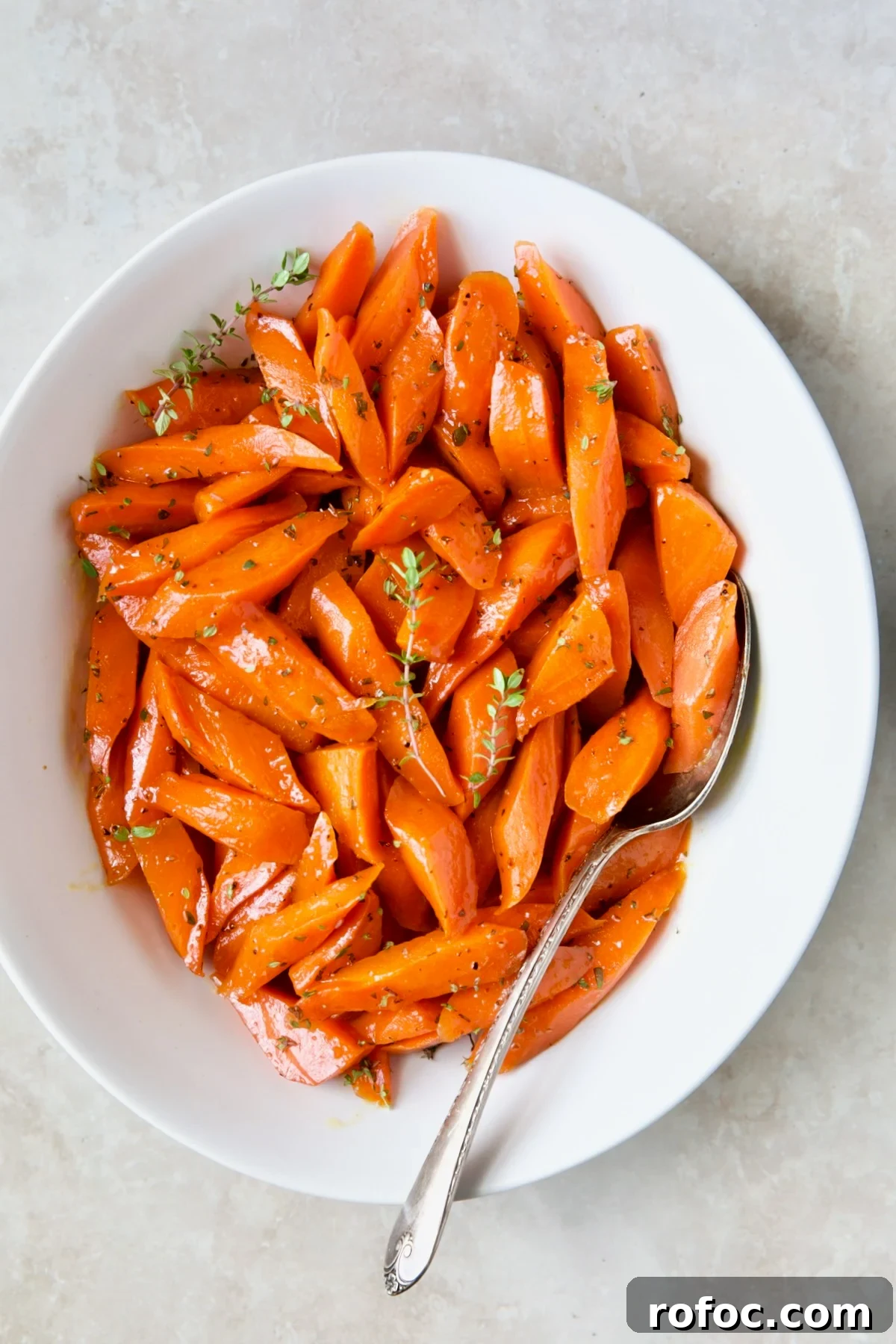 Bourbon-Glazed Carrots with Honey and Fresh Thyme 10 Bourbon-Glazed Carrots with Honey in white serving bowl garnished with fresh thyme.