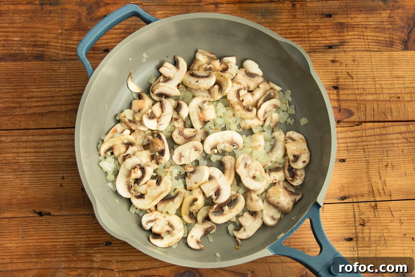 This is a picture of a skillet with onion and mushrooms cooking.