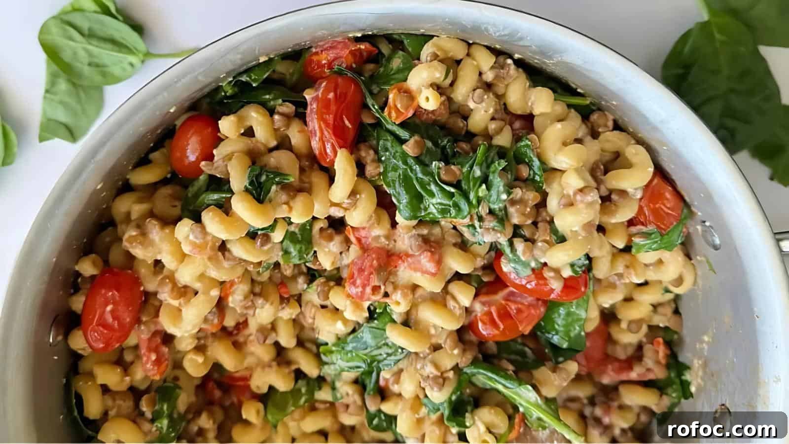 23 Vegetarian Dinners That Even Meat Eaters Will Love 20 A pot of pasta with cherry tomatoes, lentils, and spinach leaves, mixed together.