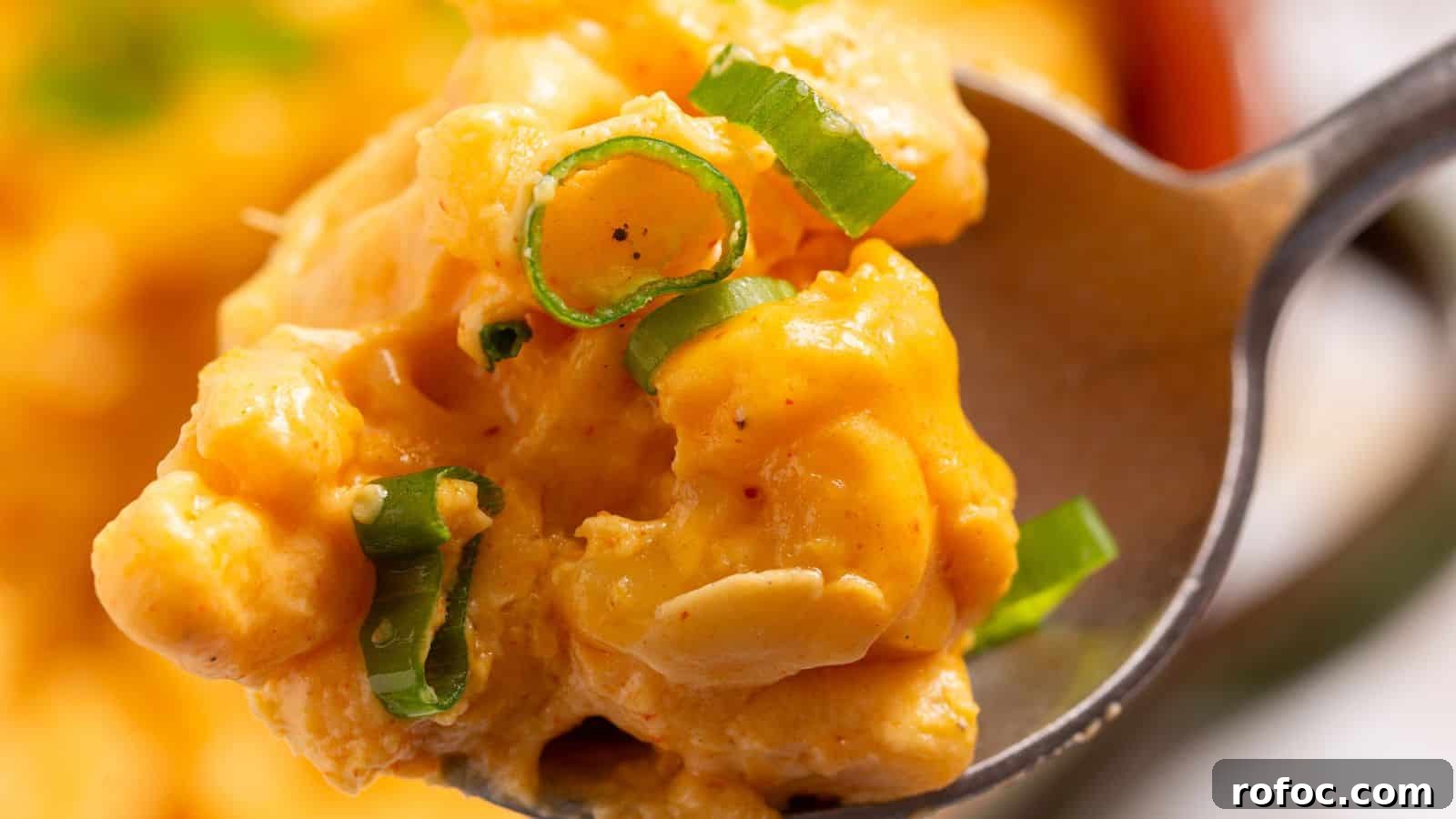 23 Vegetarian Dinners That Even Meat Eaters Will Love 4 Close-up of a spoon holding creamy mac and cheese garnished with green onions.