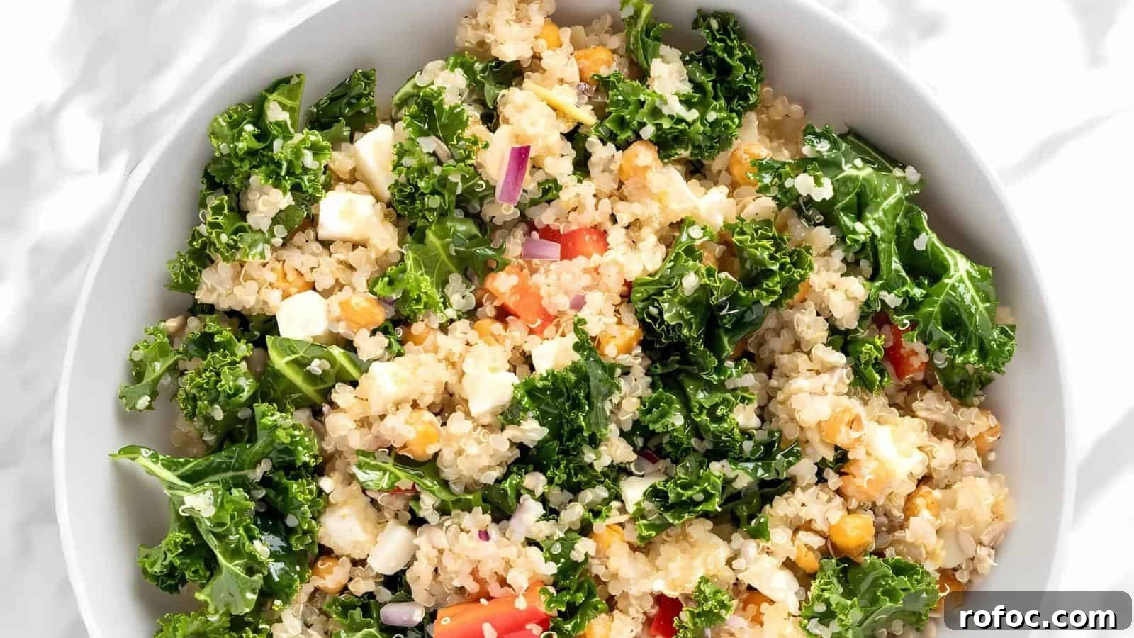 23 Vegetarian Dinners That Even Meat Eaters Will Love 7 A white bowl filled with quinoa salad, mixed with kale, red onion, tomato, feta cheese, and chickpeas.