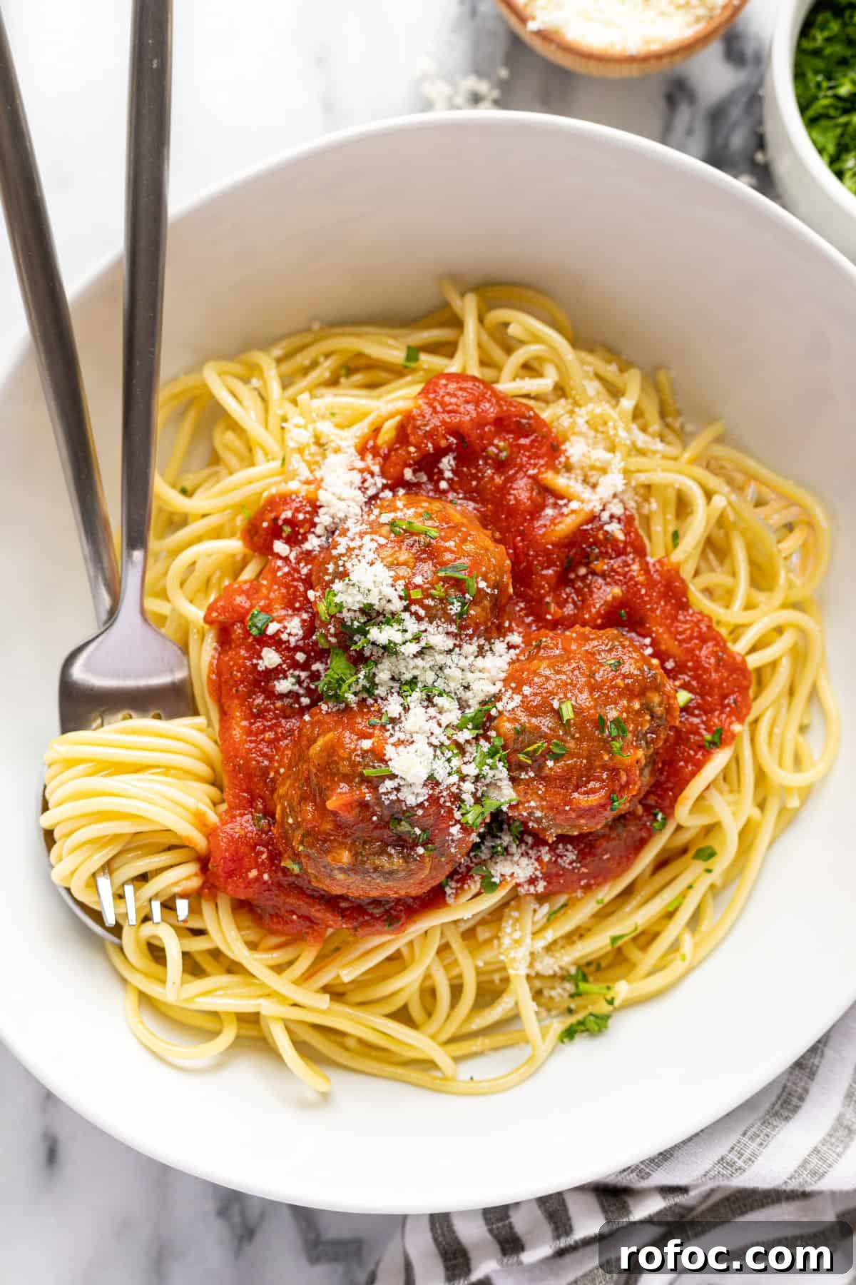 Authentic Italian Meatballs Recipe Ready in 30 Minutes 10 White bowl filled with spaghetti and hoemmade meatballs topped with grated Parmesan and parsley.