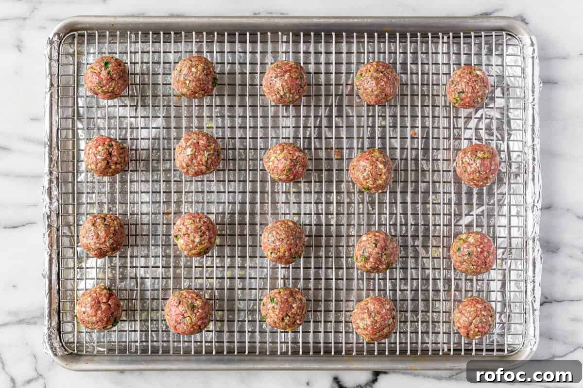Authentic Italian Meatballs Recipe Ready in 30 Minutes 7 Foil lined baking sheet with a cooling rack on top with homemade uncooked meatballs.