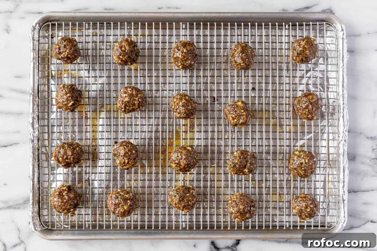 Authentic Italian Meatballs Recipe Ready in 30 Minutes 8 Foil lined baking sheet with a cooling rack on top with cooked meatballs.