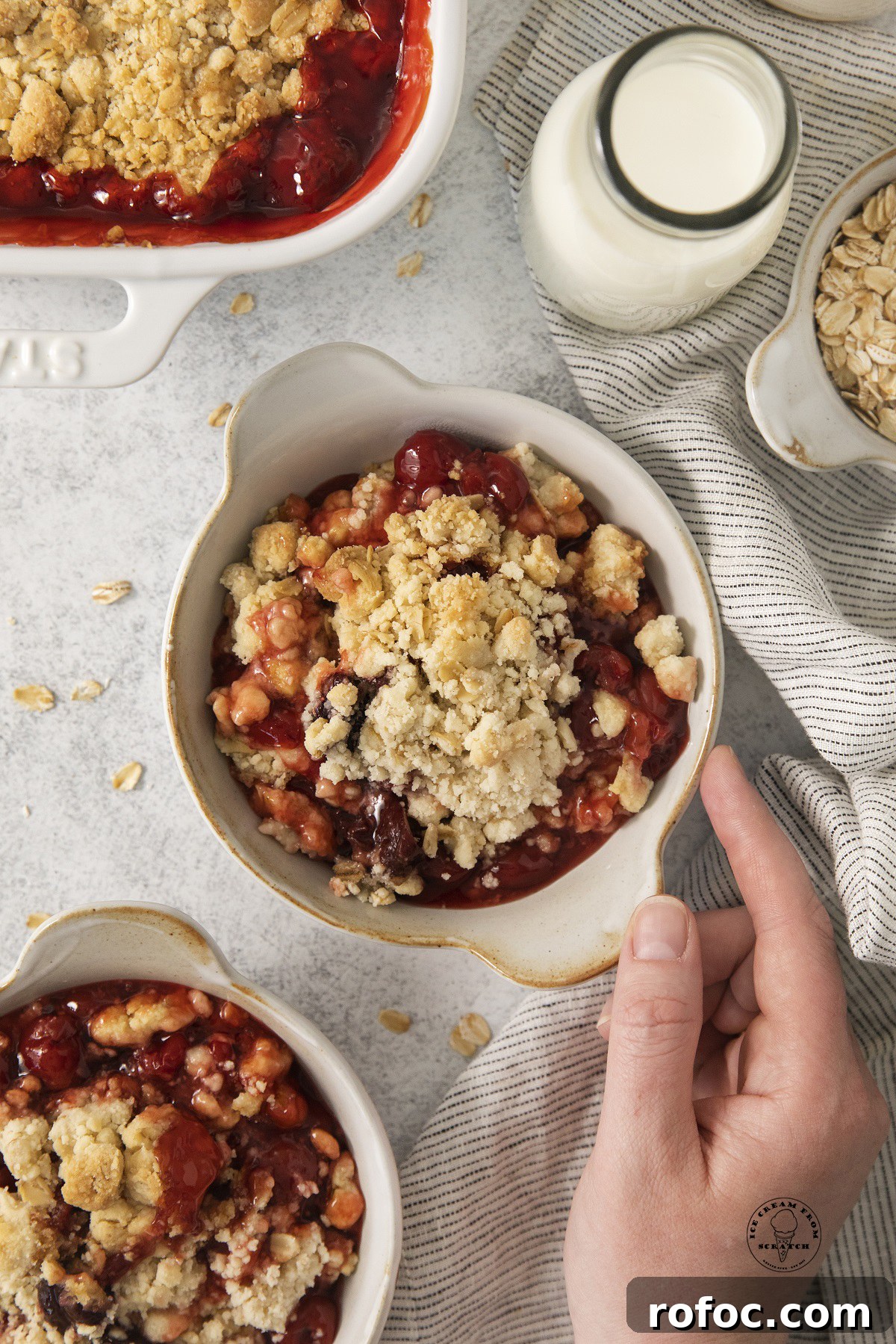 Cherry Cobbler Made with Cake Mix: Quick Cherry Dessert Recipe 5 a hand grabbing a bowl of cake mix cherry cobbler.