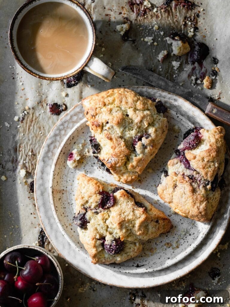 Fresh Cherry Scones: Flaky Homemade Recipe for Summer Baking 2 Three cherry scones on a baking tray with a cup of coffee.