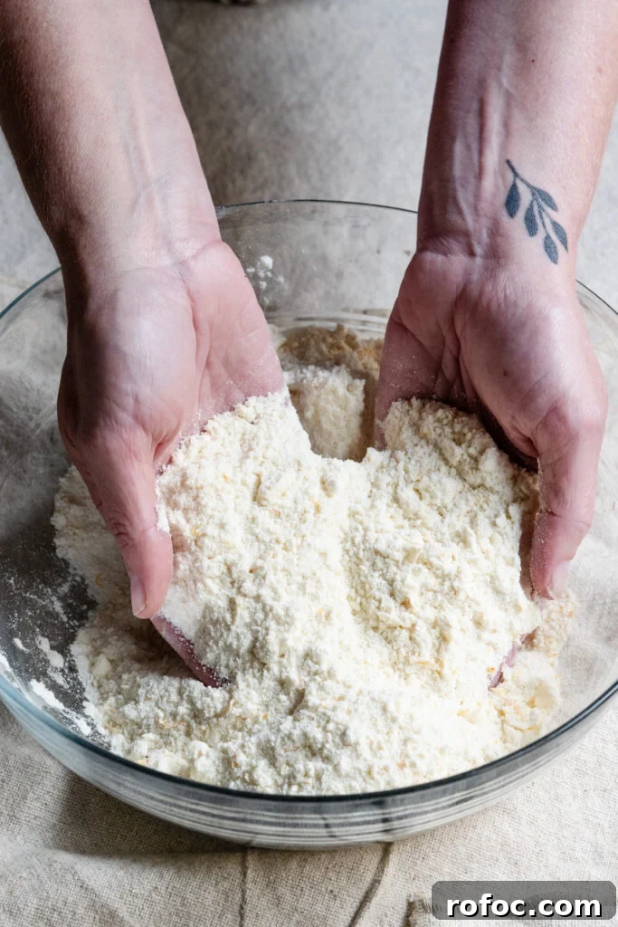 Fresh Cherry Scones: Flaky Homemade Recipe for Summer Baking 6 Two hands working butter into flour inside a mixing bowl.