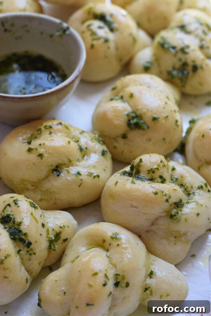 How to Make Homemade Garlic Knots: Soft, Chewy & Flavorful 2 Garlic knots on a tray with fresh parsley.