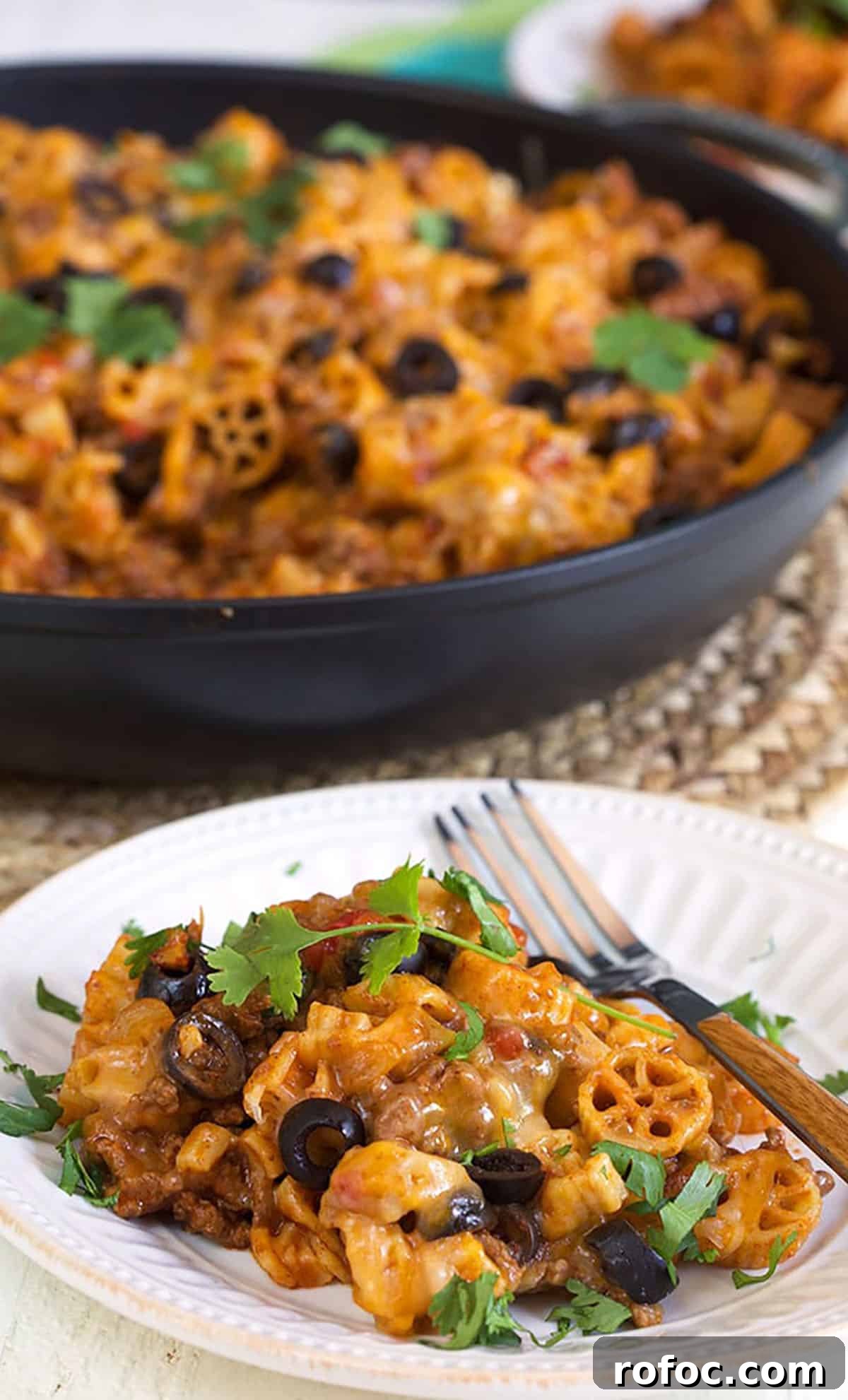 Cheesy Taco Pasta Recipe: One-Pot Mexican-Inspired Dinner 6 taco pasta on a white plate with a skillet in the background.