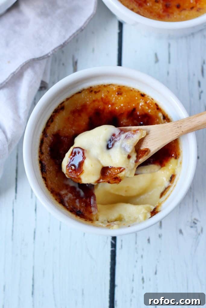 Crème Brûlée Recipe: Classic French Custard with Caramelized Top 4 creme brule in ramekin with spoon taking first bite