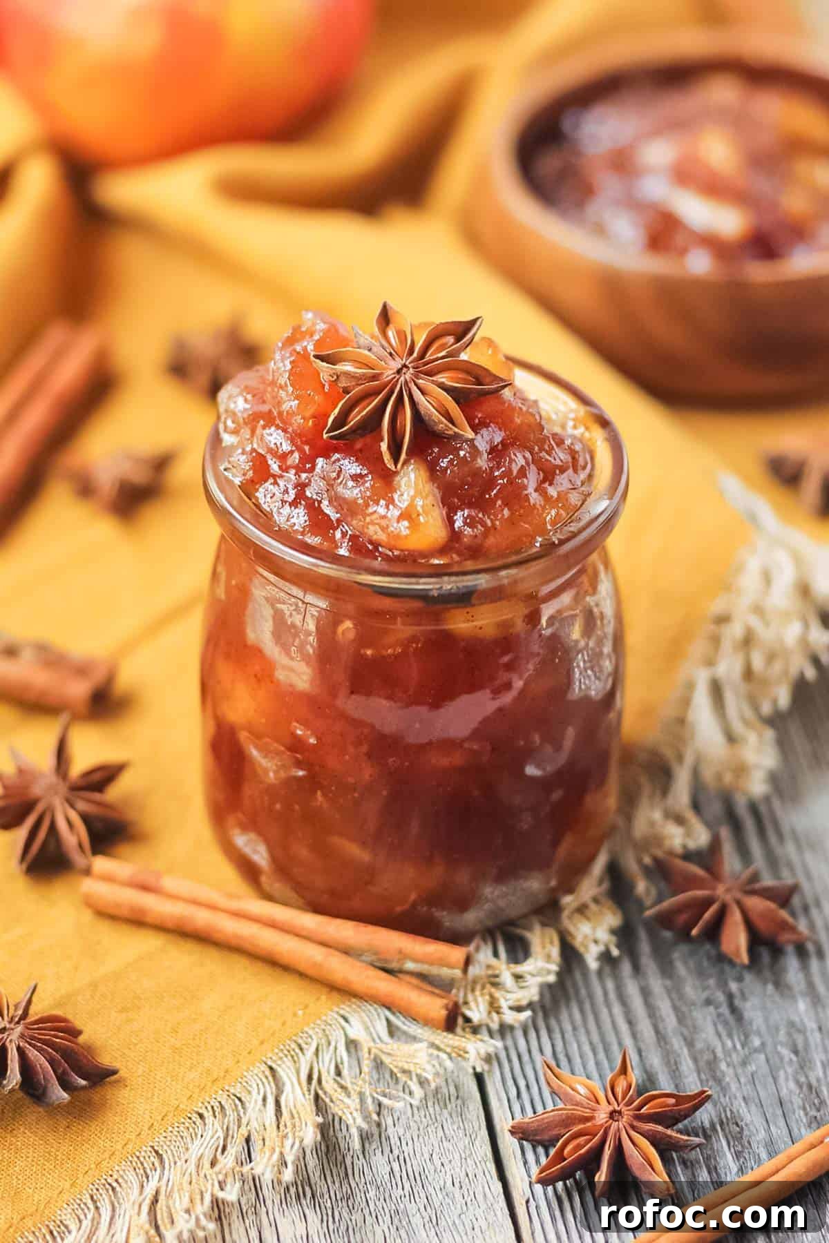 How to Make Classic Homemade Apple Jam: Simple Step-by-Step Recipe 2 apple jam in a glass jar sitting on a wooden surface.