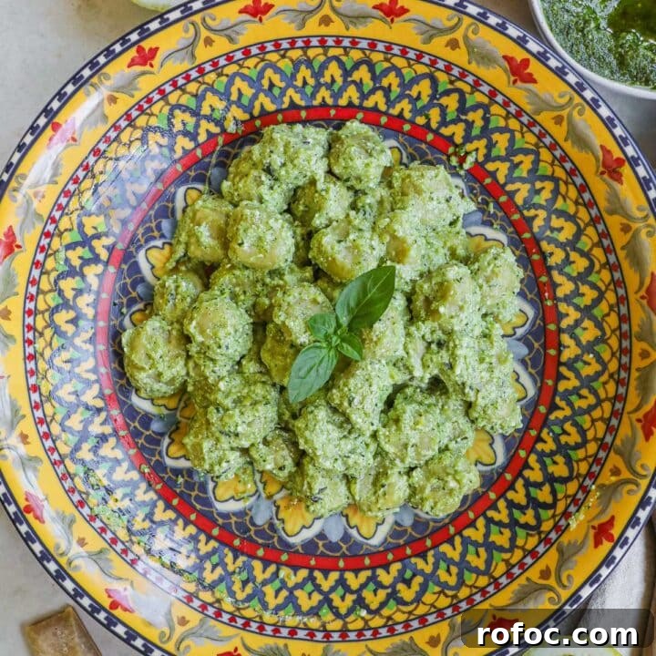 Creamy pesto gnocchi (gnocchi al pesto) in a creamy ricotta pesto with lemon zest and juice in an Italian ceramic serving bowl.