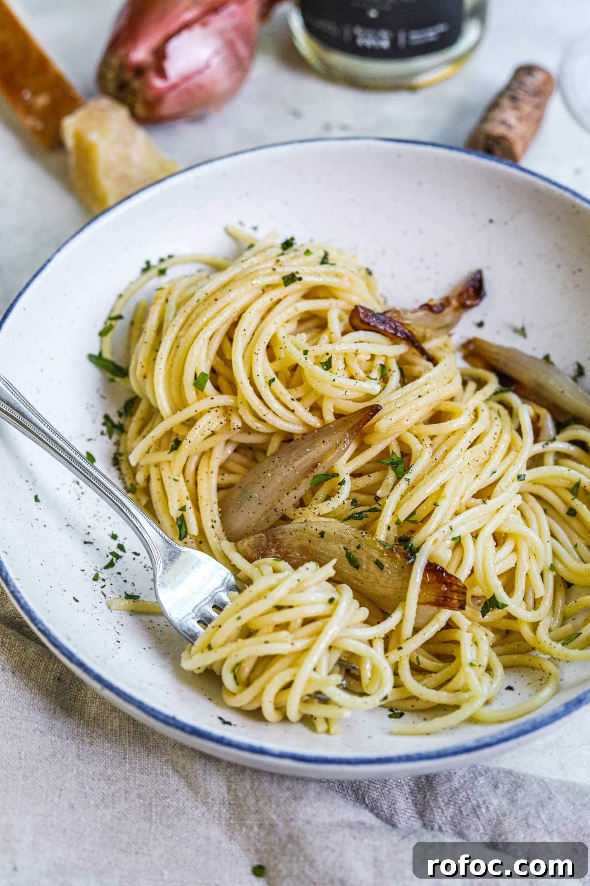 Miso Pasta with Sweet Caramelized Shallots and Toasted Sesame 7 Pasta tossed in a miso butter sauce with roasted caramelized shallots, parsley, and Parmigiano-Reggiano in a pasta bowl with a fork twirling pasta.