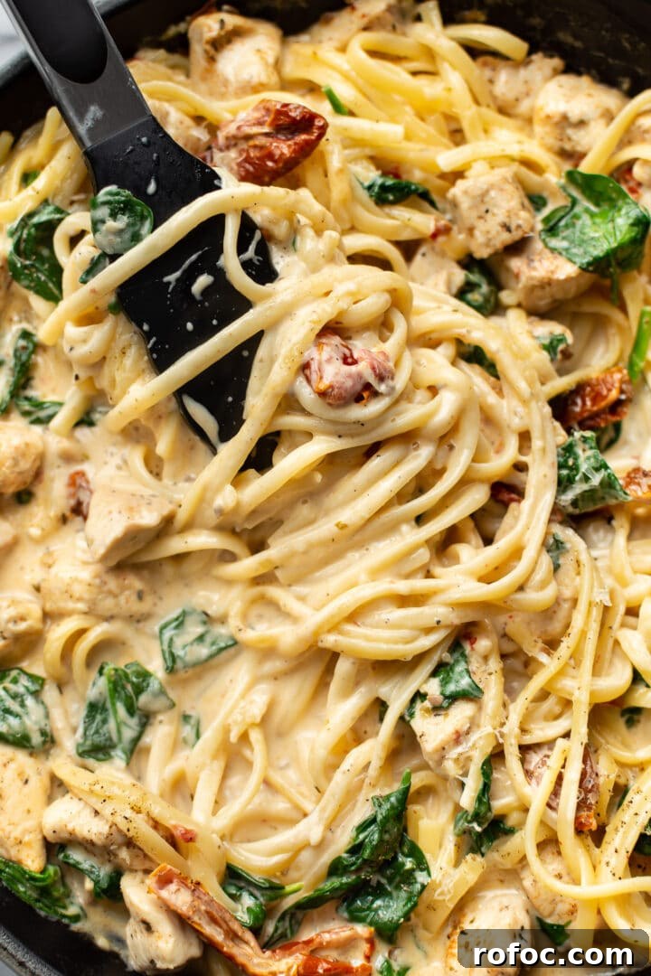 Creamy Tuscan Chicken Pasta: Garlic Parmesan Skillet Recipe 7 close-up of serving tongs serving tuscan chicken pasta in a skillet