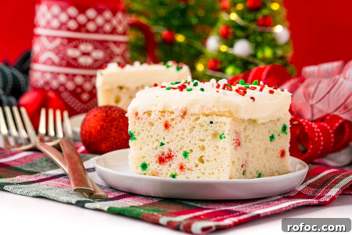 Classic Christmas Cake Recipe: Moist Fruit Cake for the Holidays 3 A slice of funfetti Christmas cake on a white plate on a holiday napkin with decor in the background.