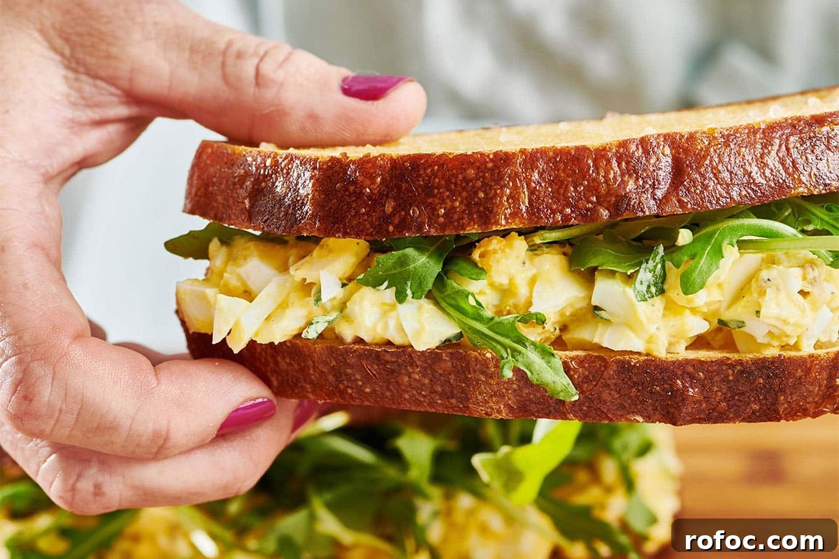 30 Refreshing No-Cook Summer Recipes for Hot Days 3 Woman holding an Egg Salad sandwich.