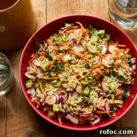 Vegetable and Brown Rice Salad with Honey Lemon Dressing in red bowl.