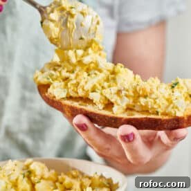 Woman spooning egg salad on bread.