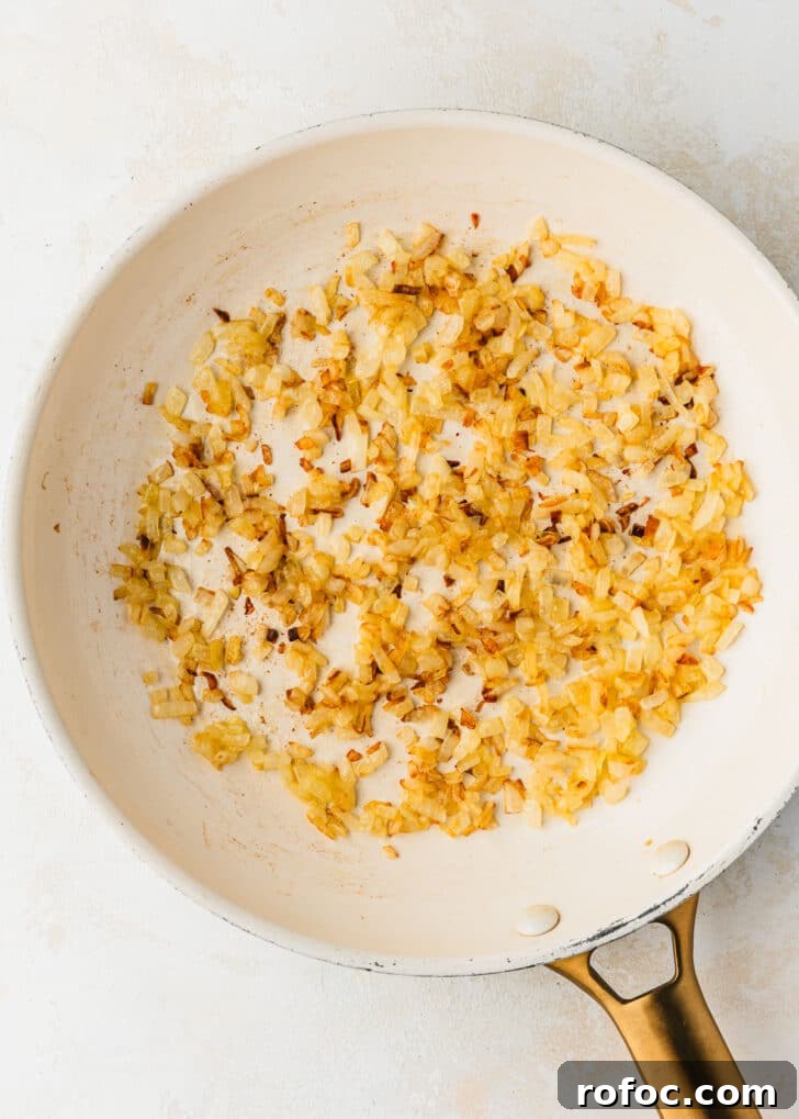 Crispy Air Fryer Chicken Meatballs Recipe 4 A white pan of sauteed onions on a white counter.