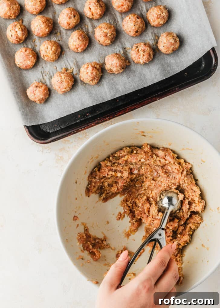 Crispy Air Fryer Chicken Meatballs Recipe 7 A hand using a scoop to divide meat for air fryer chicken meatballs.
