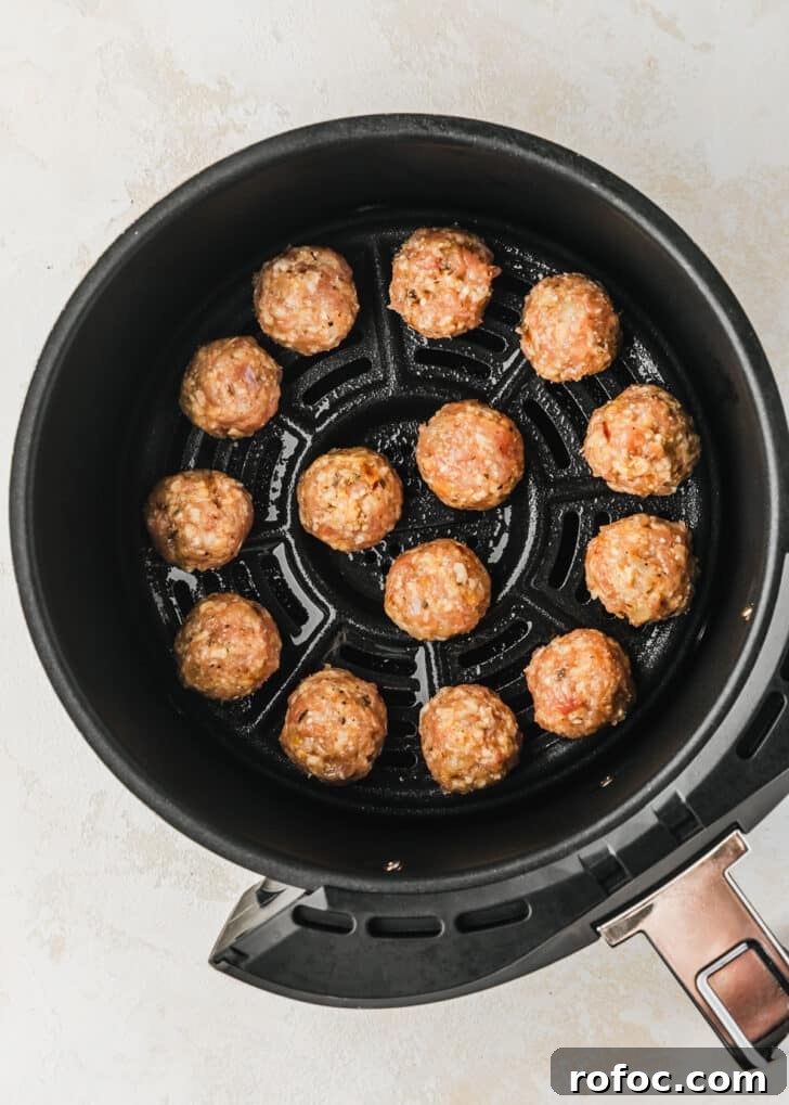 Crispy Air Fryer Chicken Meatballs Recipe 8 Raw chicken meatballs in an air fryer basket.