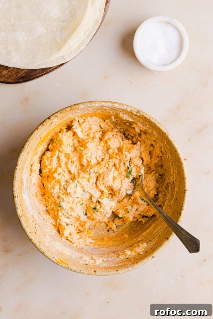 Spicy Buffalo Chicken Taquitos Recipe for Game Day Snacks 6 Filling for buffalo chicken taquitos mixed in a large bowl