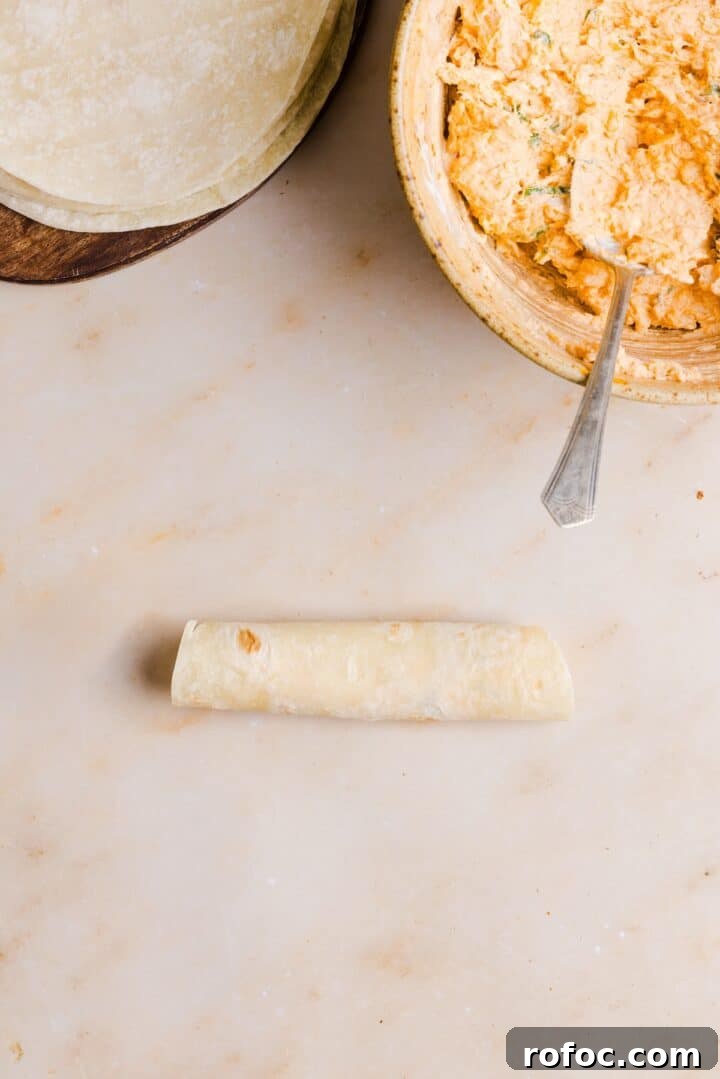 Spicy Buffalo Chicken Taquitos Recipe for Game Day Snacks 8 Buffalo chicken taquito rolled on a beige kitchen counter
