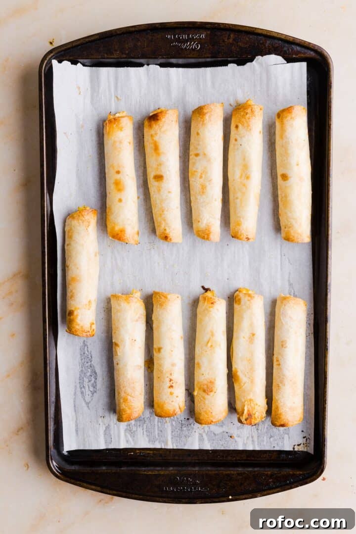 Spicy Buffalo Chicken Taquitos Recipe for Game Day Snacks 10 Buffalo chicken taquitos baked and golden brown on a parchment-lined baking tray