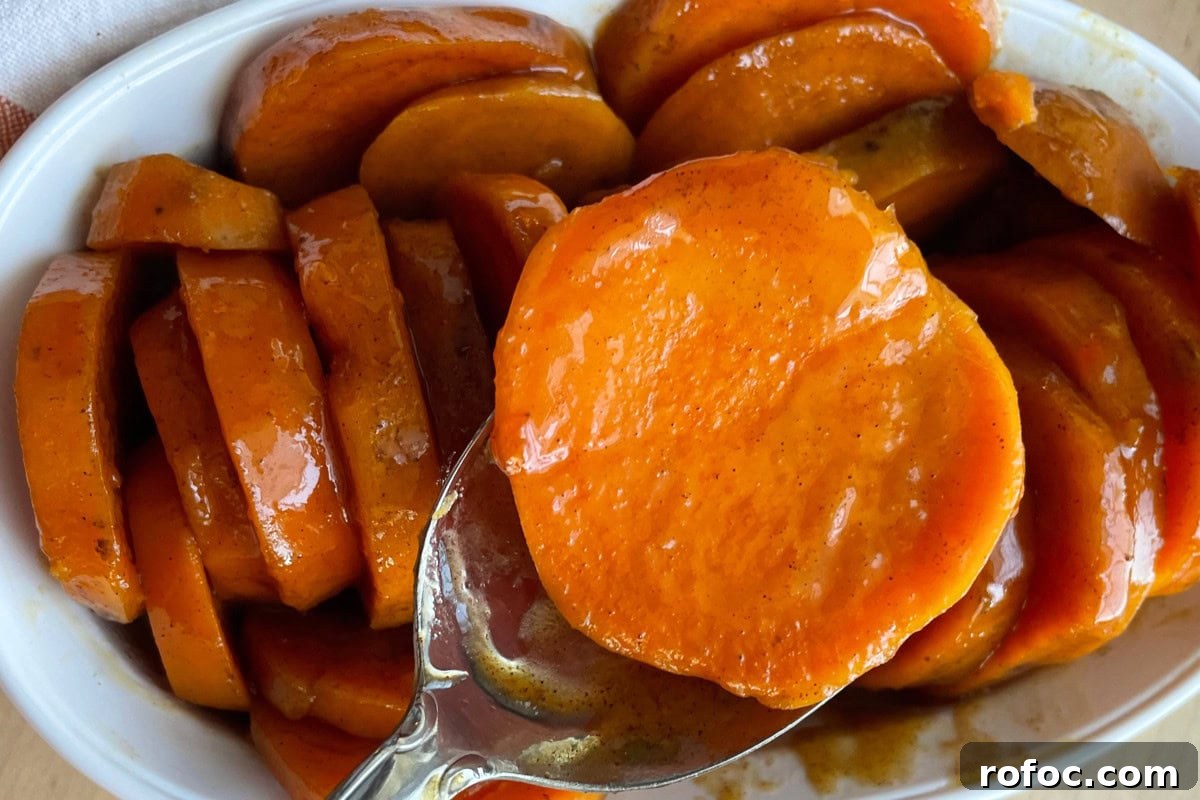 12 Delicious Easter Crockpot Recipes for a Stress-Free Holiday 13 A close-up of glazed candied sweet potatoes in a white dish.