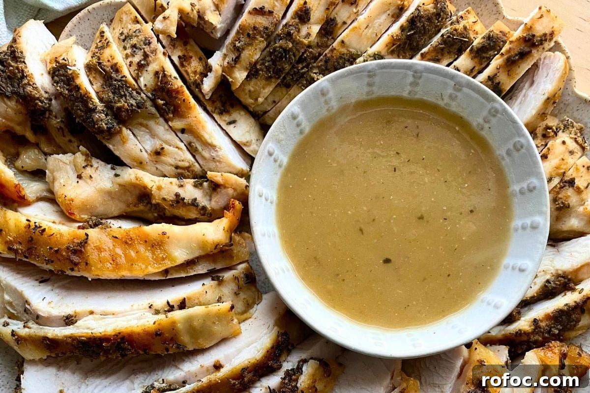 12 Delicious Easter Crockpot Recipes for a Stress-Free Holiday 3 Sliced herb-crusted turkey breast arranged on a plate next to a bowl of gravy.