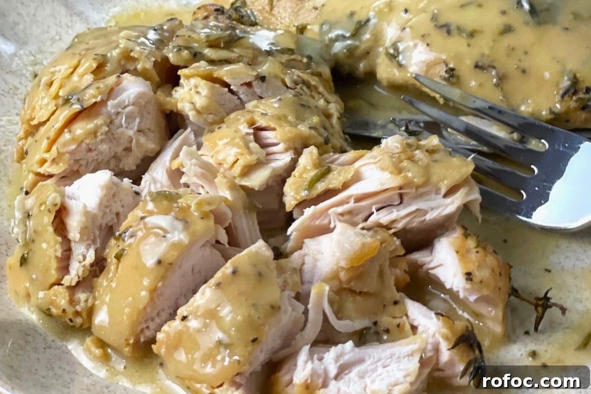 12 Delicious Easter Crockpot Recipes for a Stress-Free Holiday 5 A close-up of sliced chicken breast topped with a creamy herb sauce on a plate with a fork.