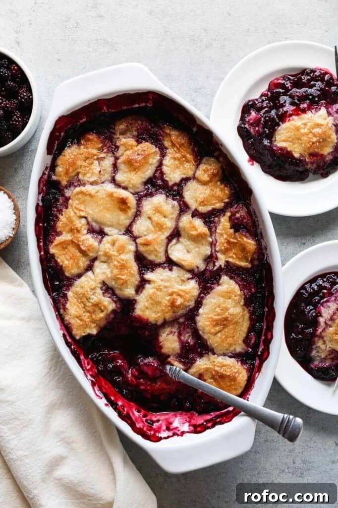 a baking dish of gluten free blackberry cobbler with two plates dished up