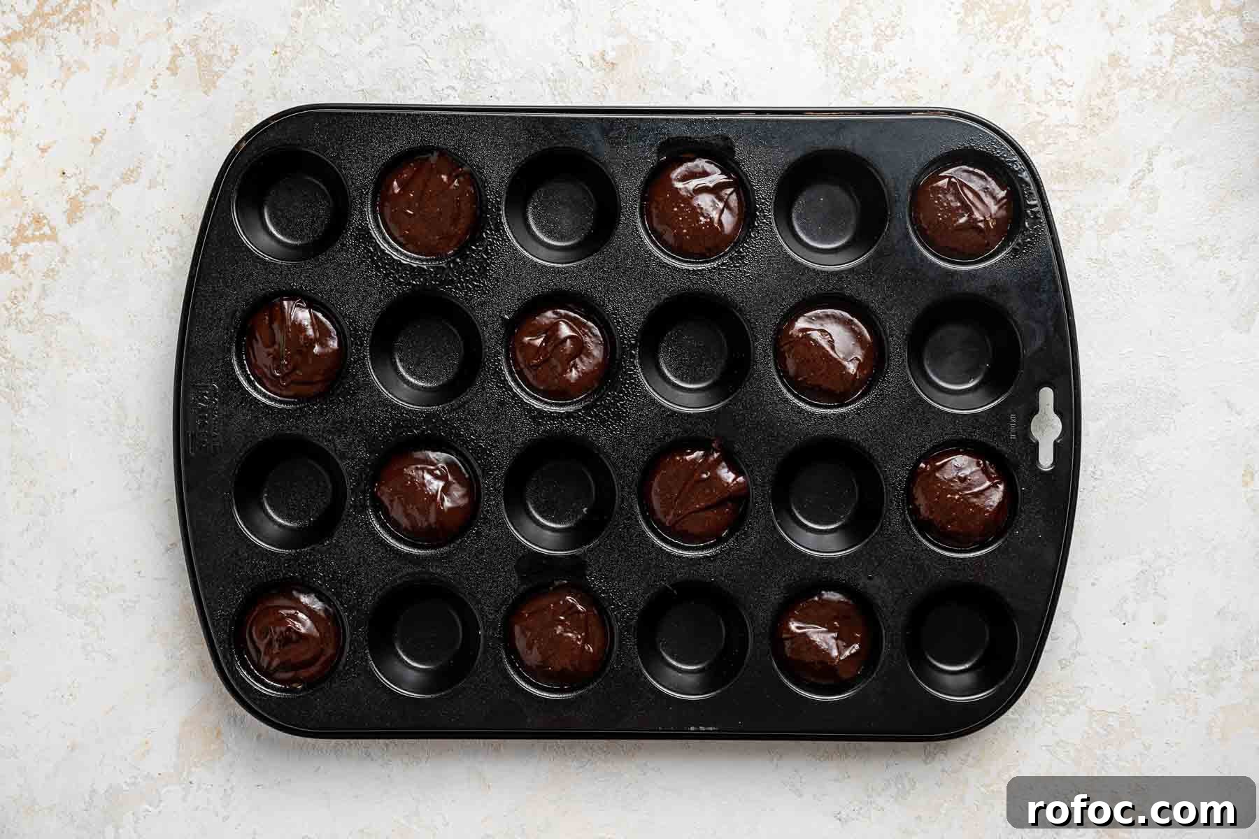 Cheesecake Brownie Bites: Mini Dessert Recipe for Parties 11 Two bite brownies going into mini muffin pans before baking.
